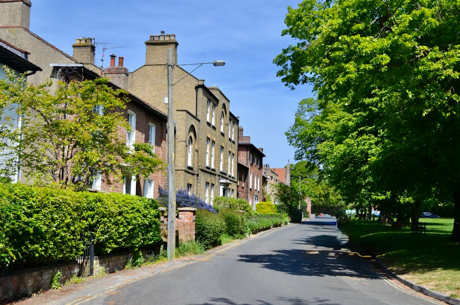 A close-up view of a traditional street sign mounted on a weathered brick wall, indicating the intersection of Branch Hill and West Heath Road. The sign features individual dark brown tiles with white painted lettering, including the words 'TO BRANCH HILL' and 'WEST HEATH RD,' with a decorative ampersand between the street names. The brick wall behind the sign displays a mix of dark and light brown tones with patches of green moss or algae growth, suggesting outdoor exposure and age. To the right of the sign, a small white ceramic hand pointing in the direction of the road is visible, adding a vintage or artistic touch. The image captures an urban or suburban setting in daylight, with no additional background details visible. This type of street signage and environment aligns with common features found in London neighborhoods, where independent waste collection and local authority services might serve residential street addresses.